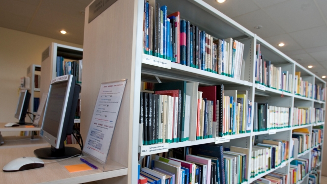 Bibliotēkas grāmatu plaukts ar datoru