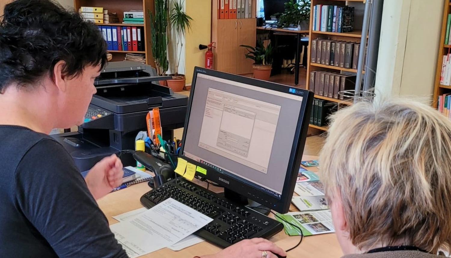 Bibliotekāre datorā aizpilda pabalsta pieteikuma veidlapu apmeklētājai